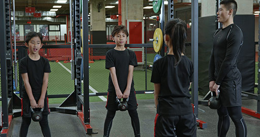 Active Chinese children having exercise class with their coach in gym,4K