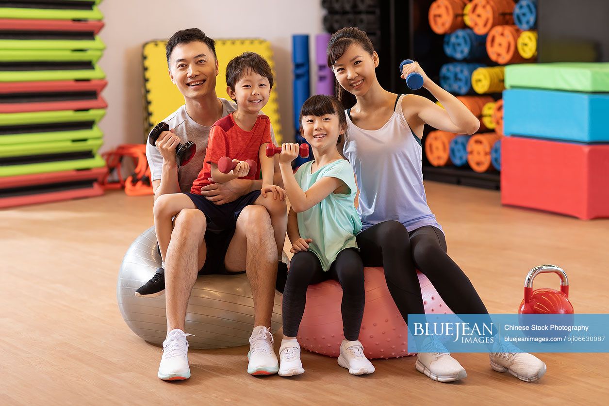 Happy young Chinese family exercising in gym