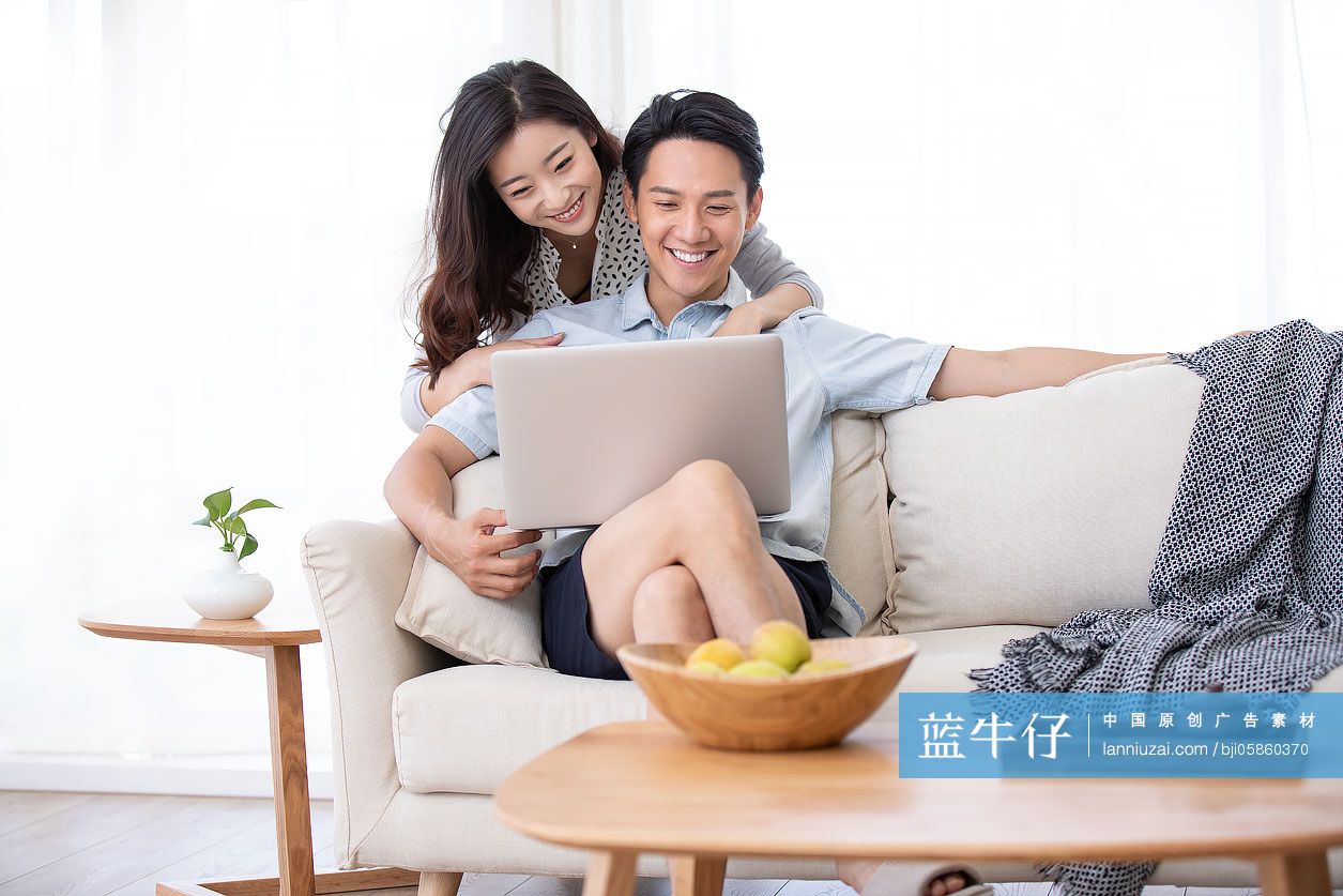 快乐的年轻情侣在客厅使用笔记本电脑