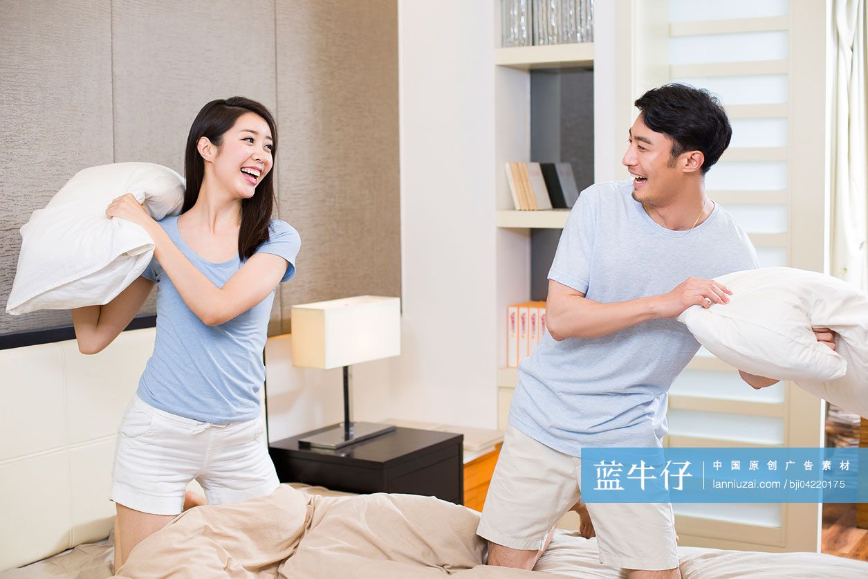 年轻夫妇在卧室打枕头仗