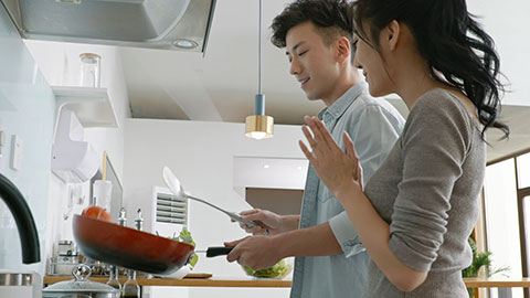 Happy young Chinese couple cooking in kitchen,4K