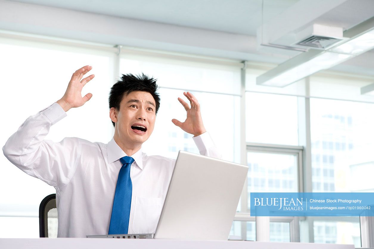 Frustrated Chinese office worker at his desk