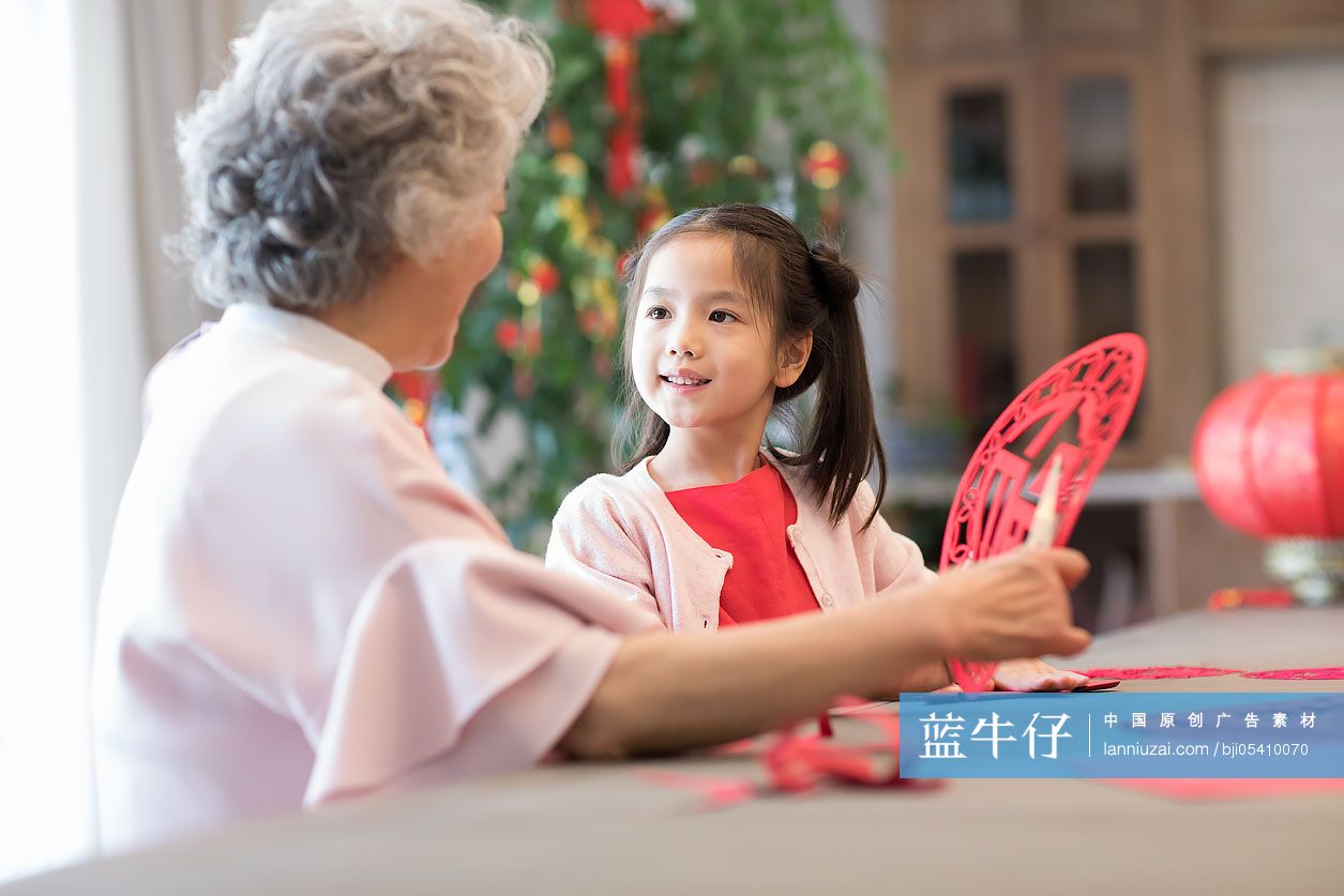 快乐的奶奶教孙女剪新年窗花