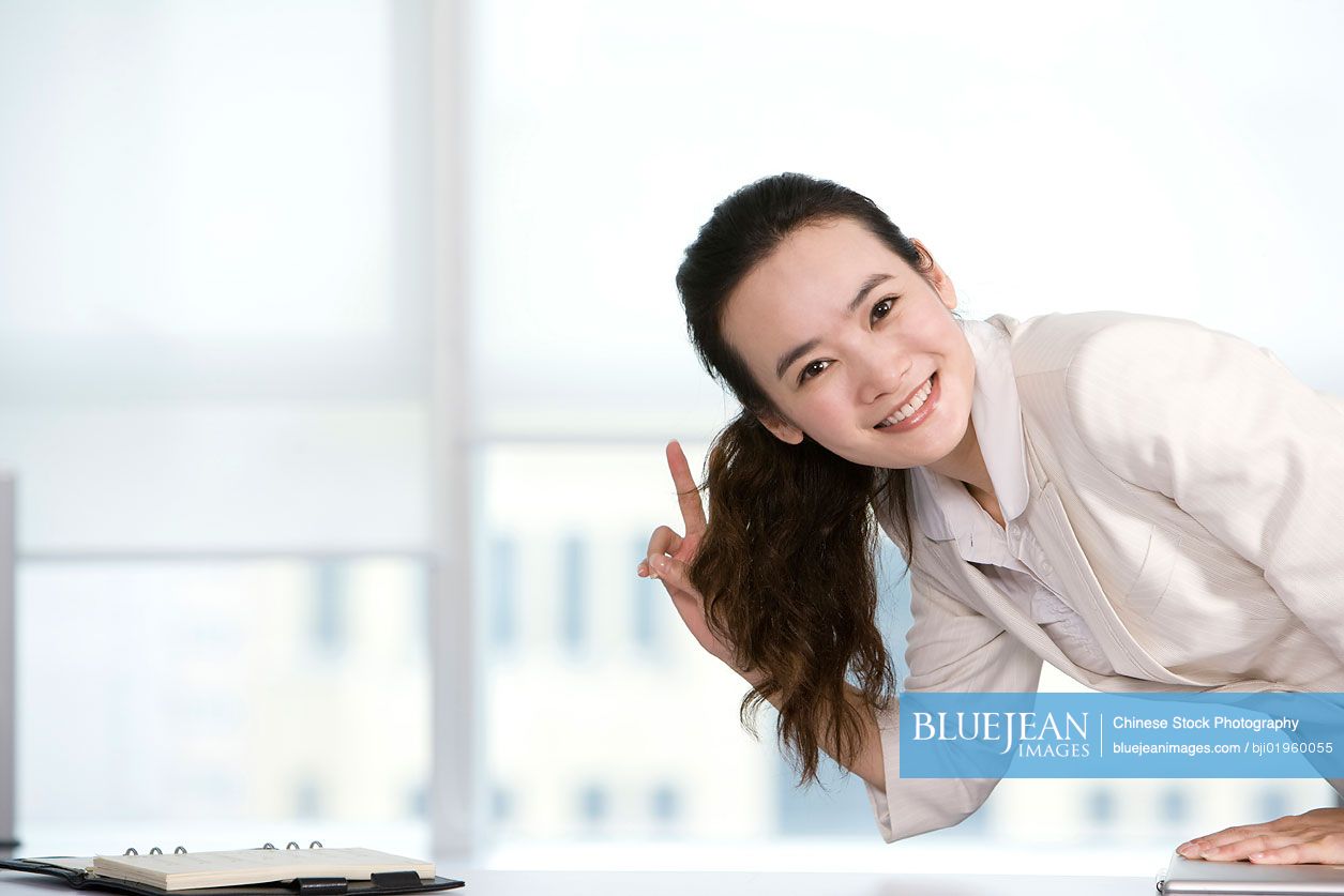 Happy Chinese office worker at her desk