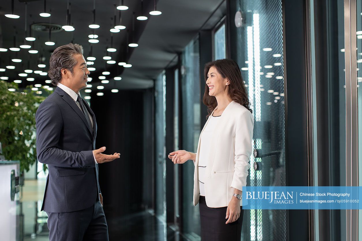 Two successful Chinese business people in office hallway