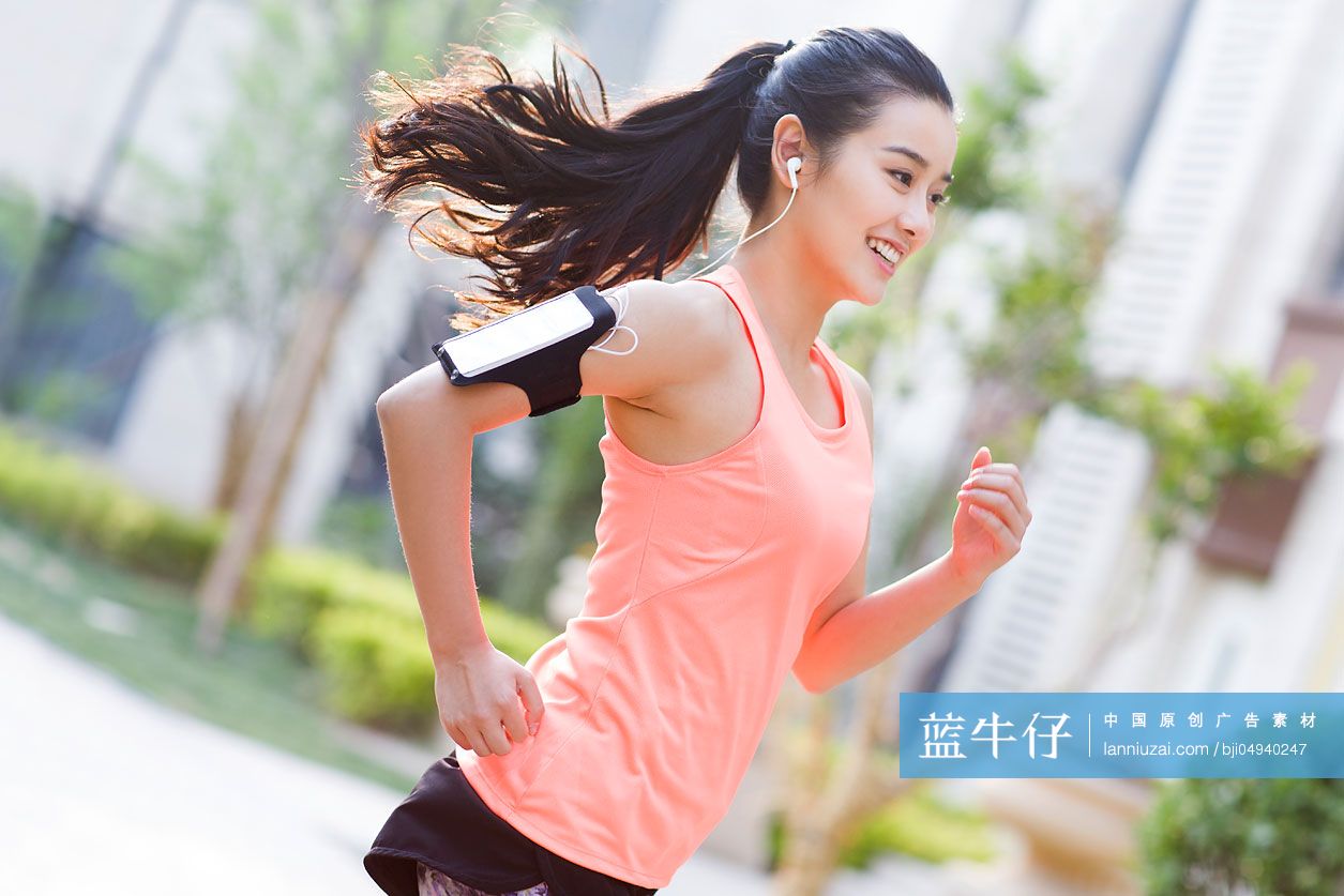 年轻女子在户外边听音乐边跑步