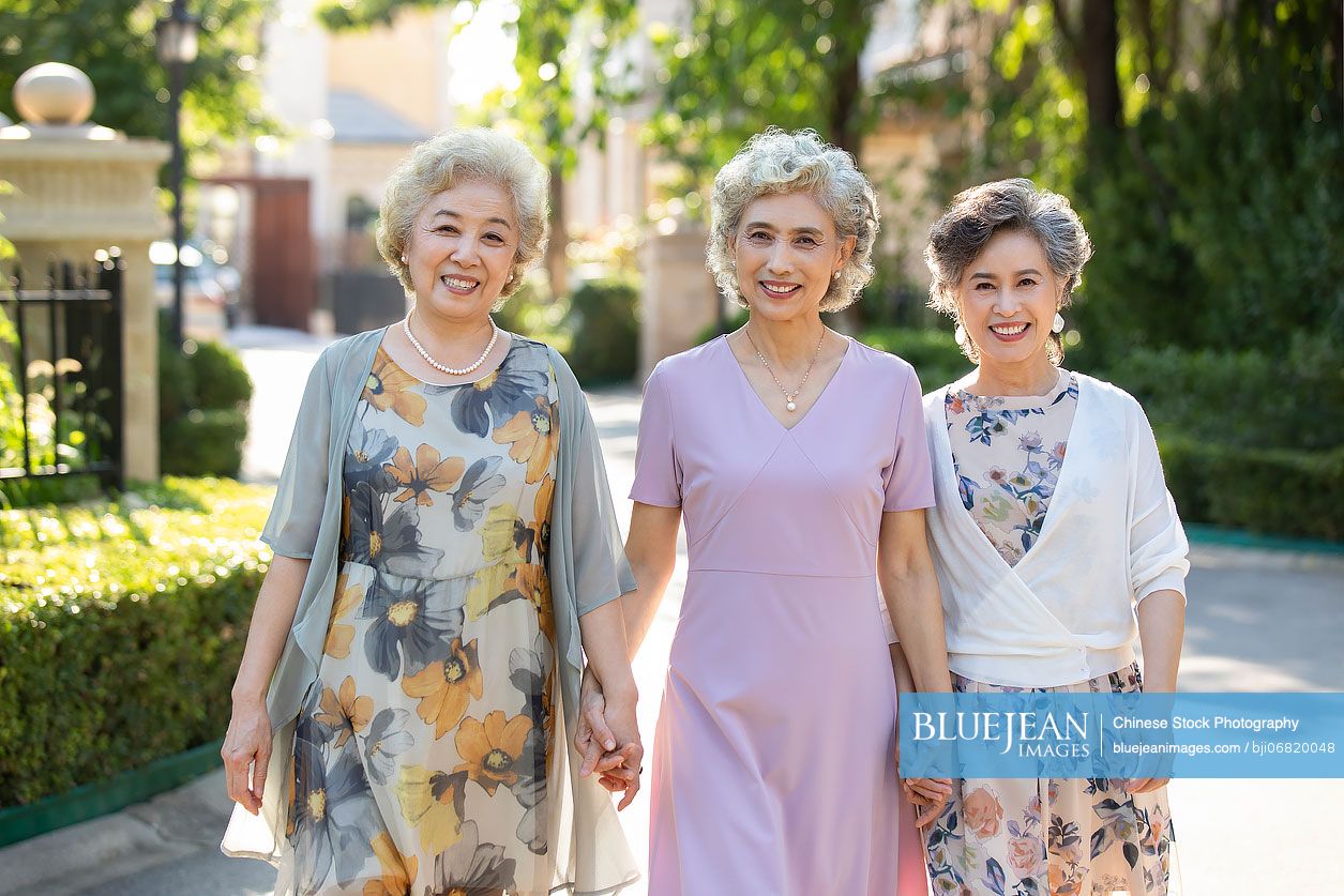 Happy senior Chinese friends strolling outside