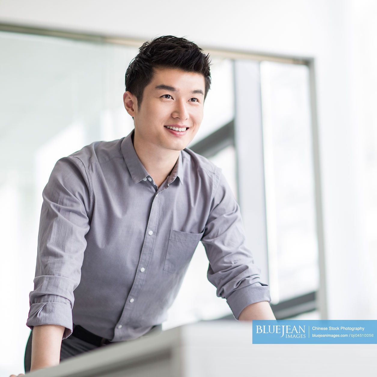 Young Chinese businessman standing in office