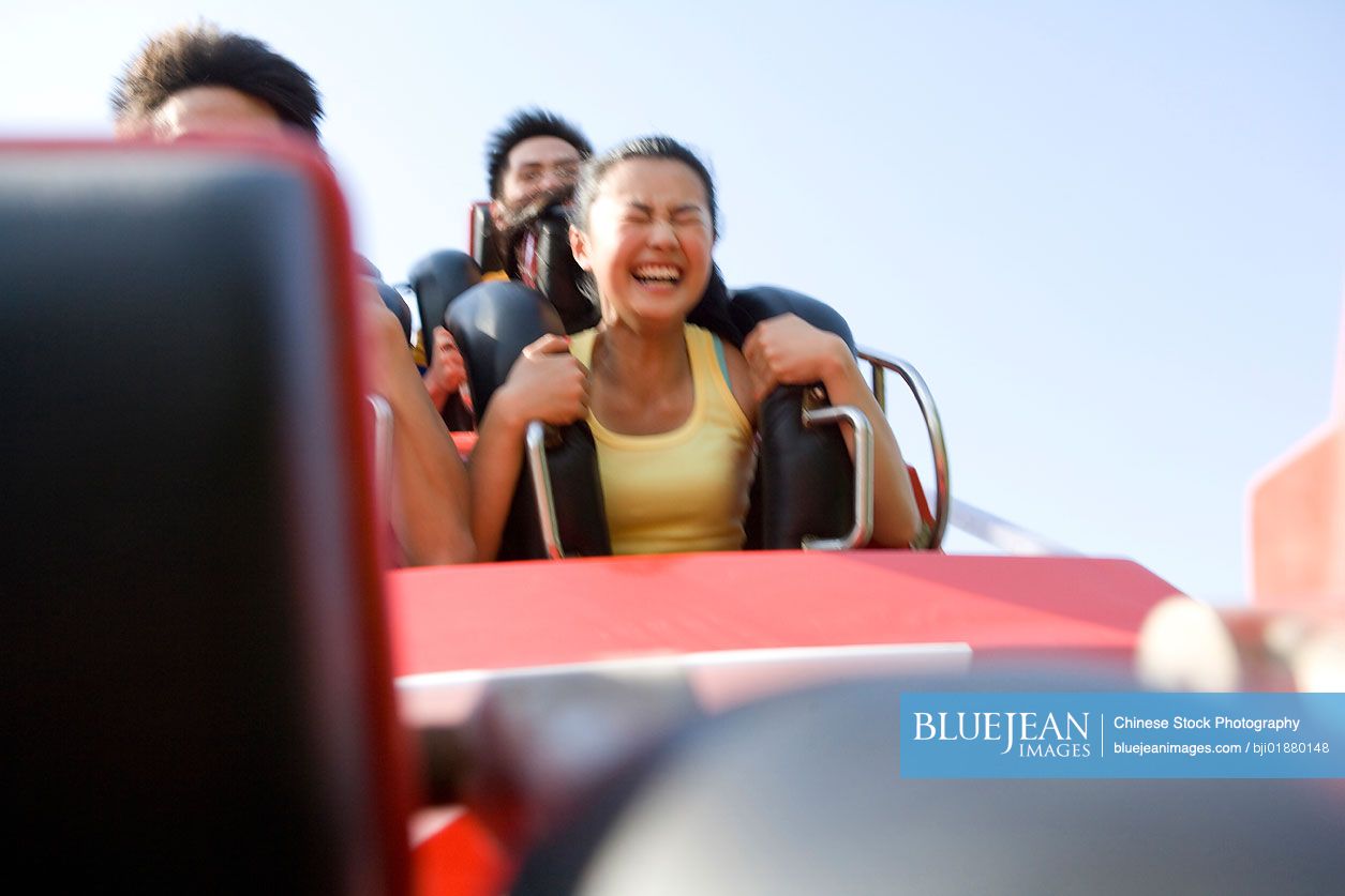 Young Chinese people riding a rollercoaster