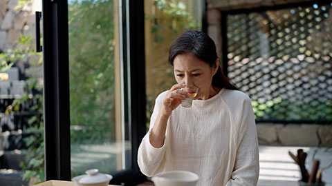 Elegant mature Chinese woman drinking tea in tea room,4K