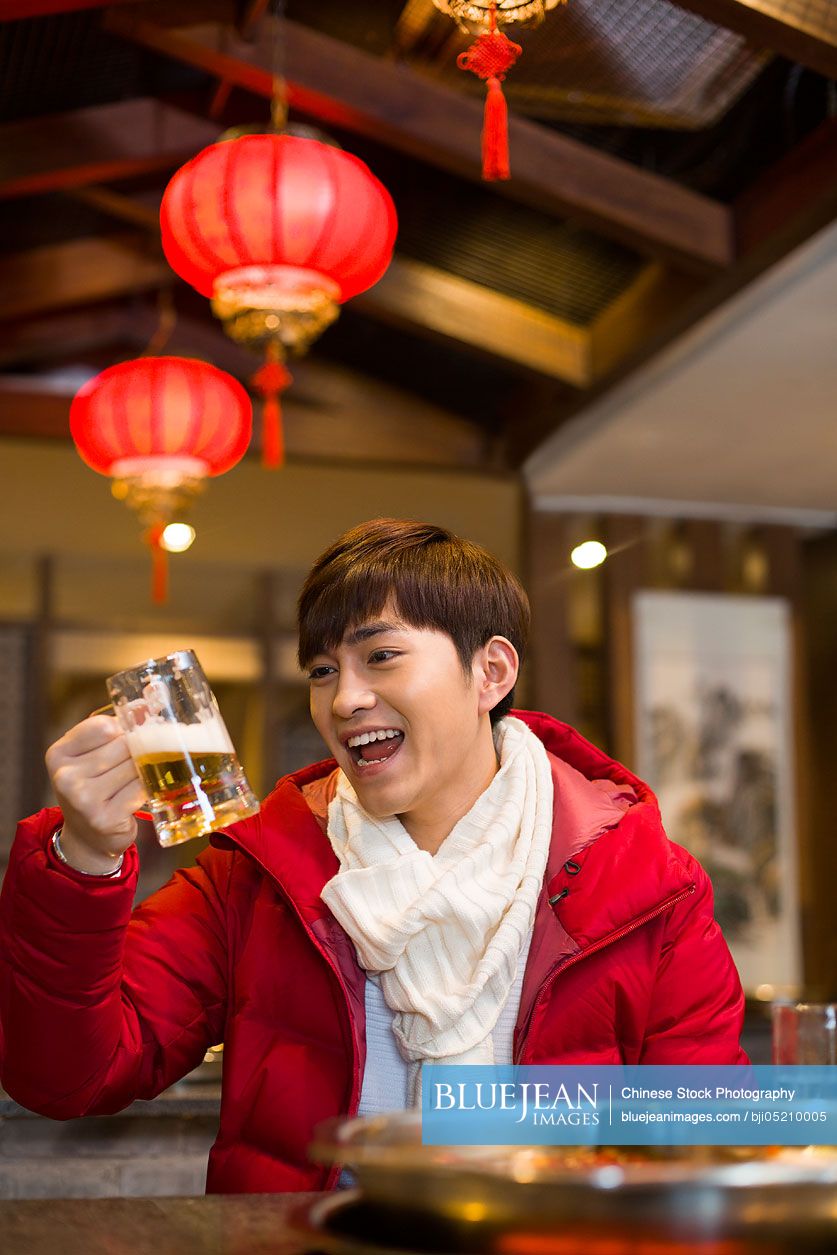 Young Chinese man drinking beer in hotpot restaurant