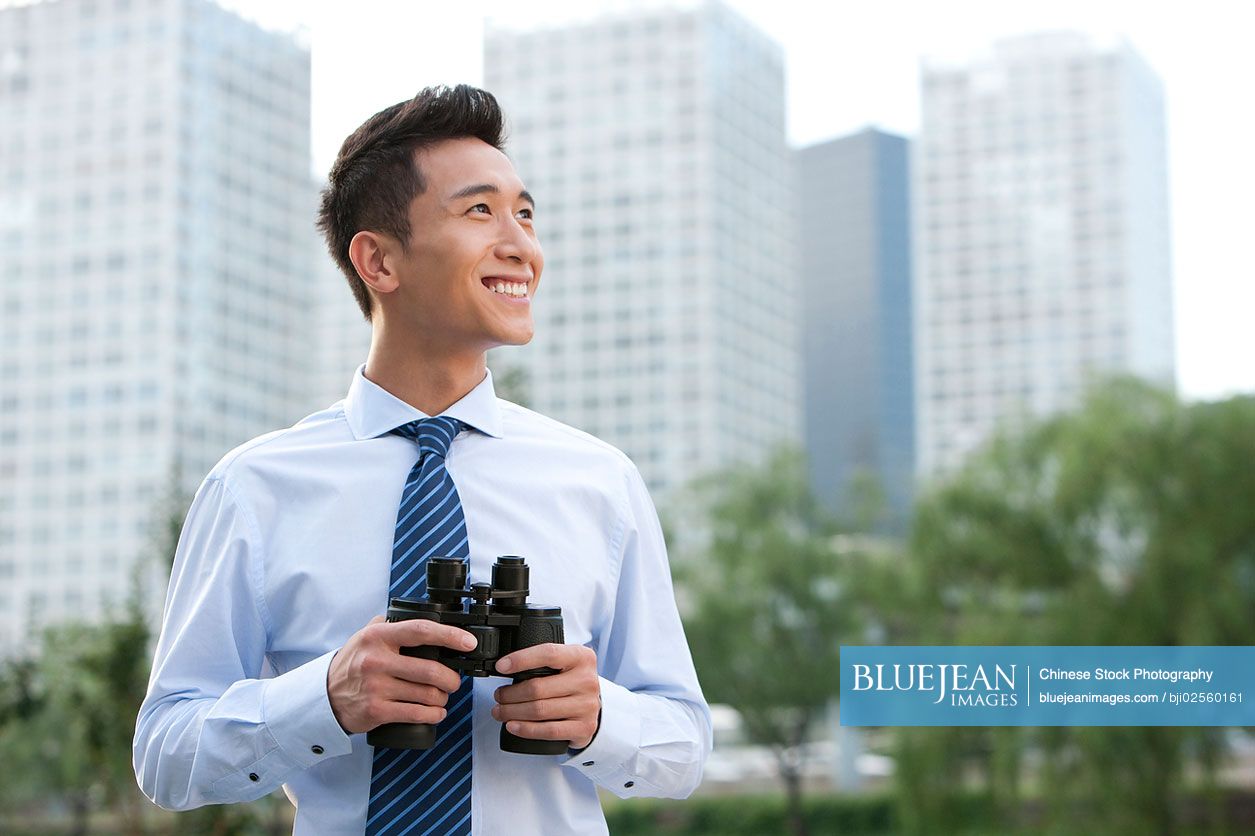 Chinese businessman holding binoculars