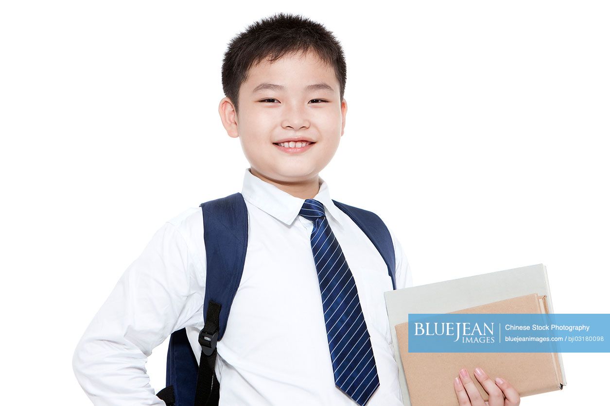 Portrait of confident Chinese schoolboy with books