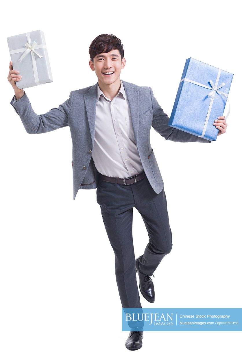 Happy young Chinese man holding gift boxes