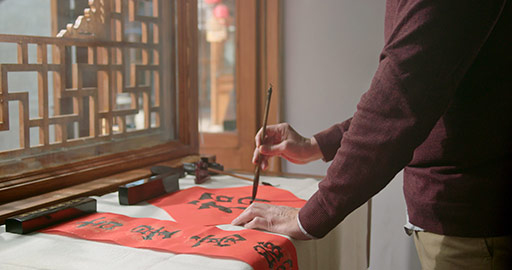 Happy senior Chinese man writing calligraphy on couplets,4K