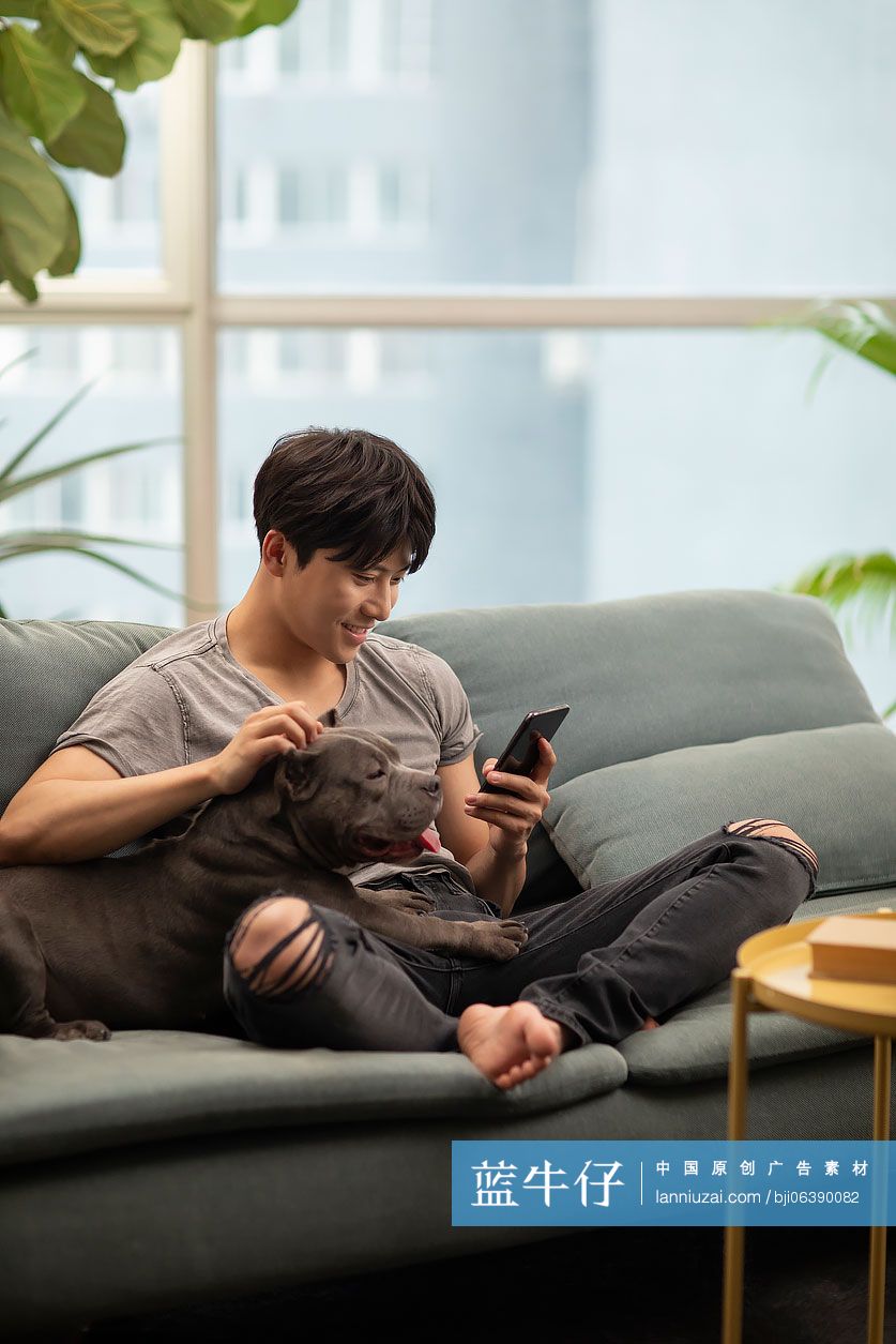 年轻男士和宠物狗在沙发上