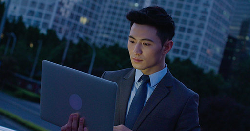 Young Chinese businessman using laptop outdoors,4K