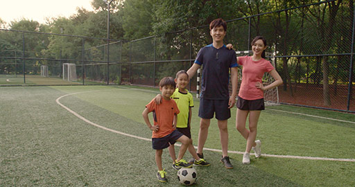 Happy young Chinese family playing football on soccer field,4K