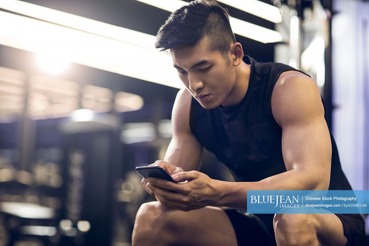 Young Chinese man taking a break from workout at gym