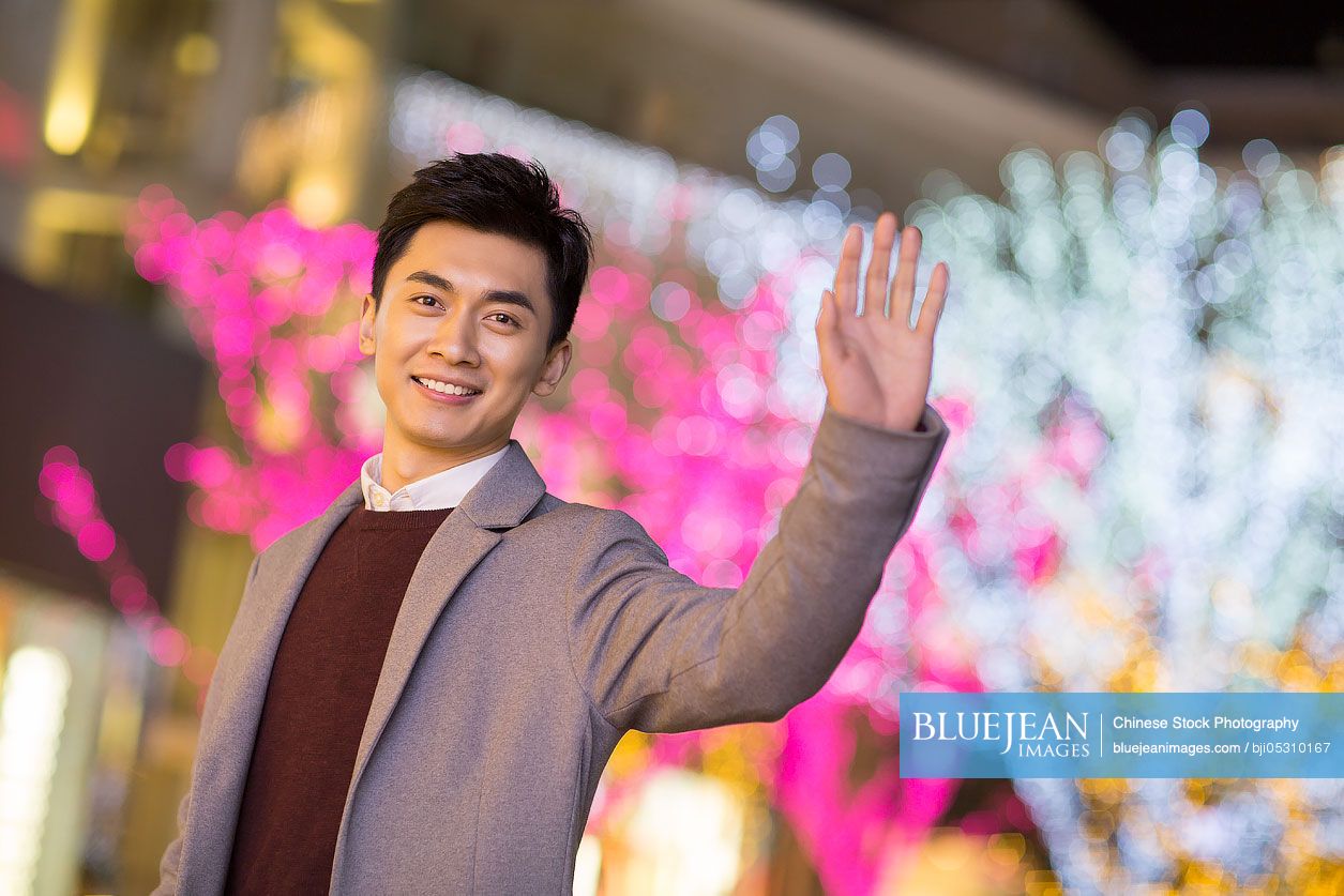 Cheerful young Chinese man waving