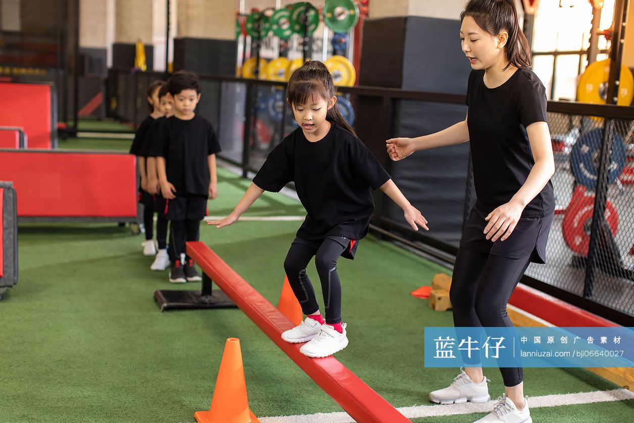 儿童在教练的指导下练习走平衡木