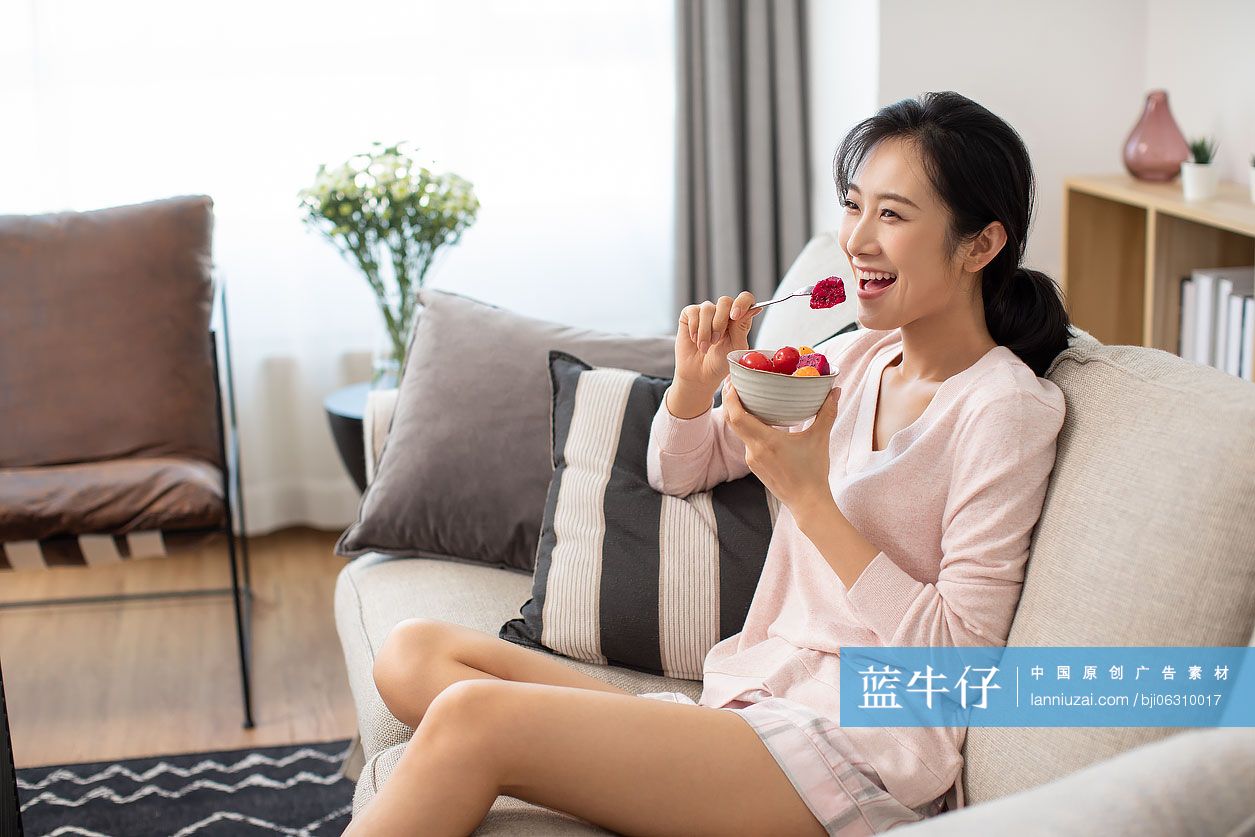 快乐年轻女士在家吃水果沙拉