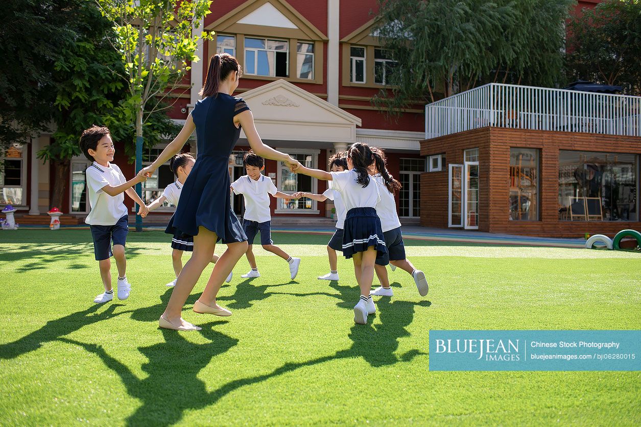 Chinese teacher and students playing in kindergarten playground