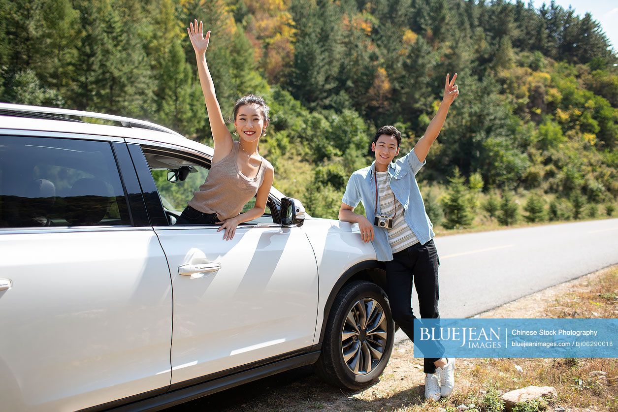 Happy young Chinese couple enjoying road trip