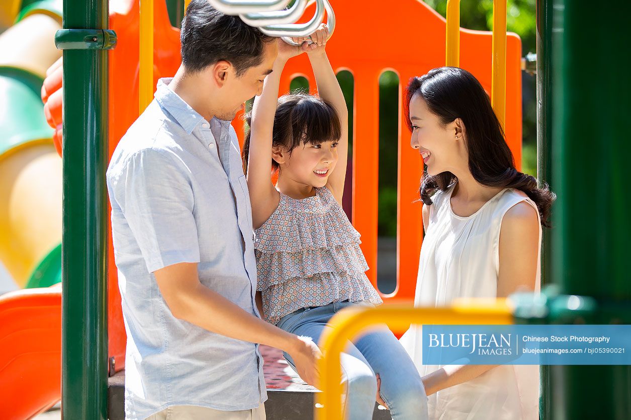 Happy young Chinese family playing in amusement park