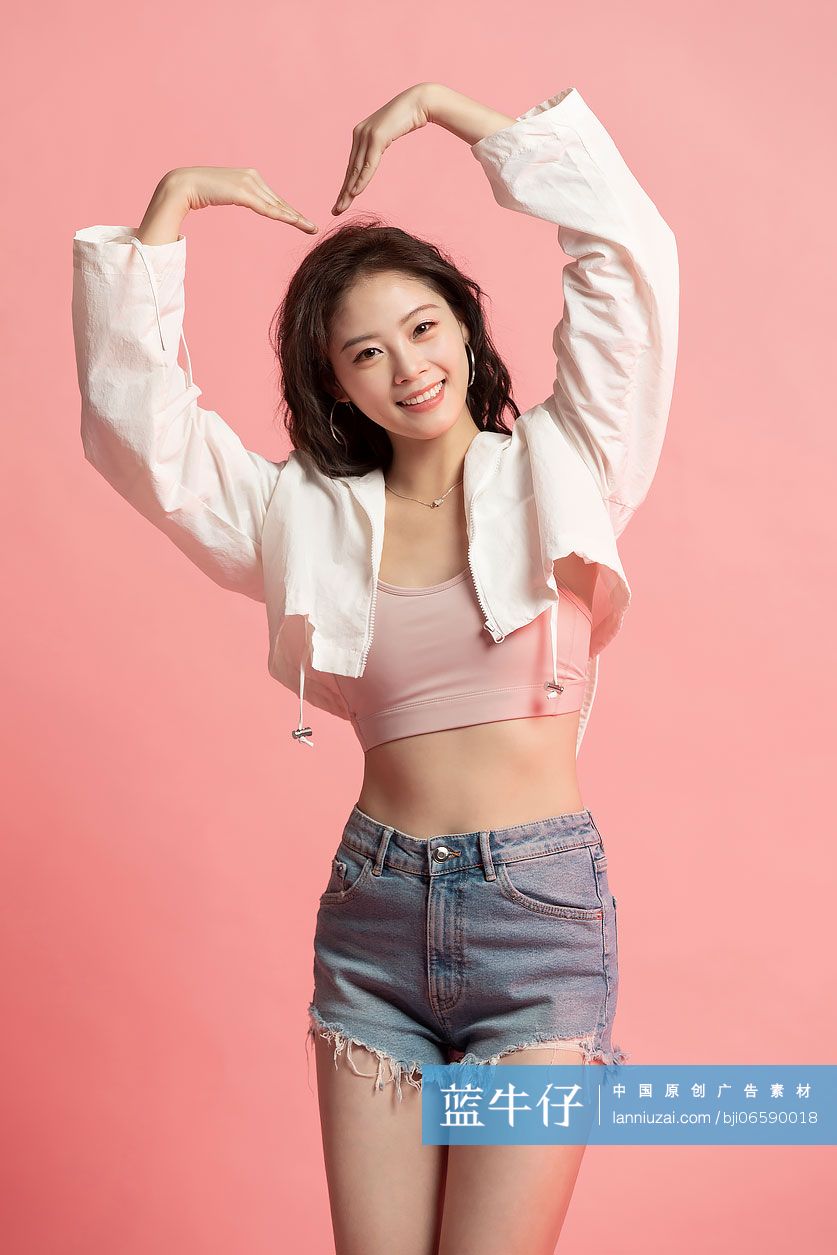 可爱的年轻女孩做心型手势