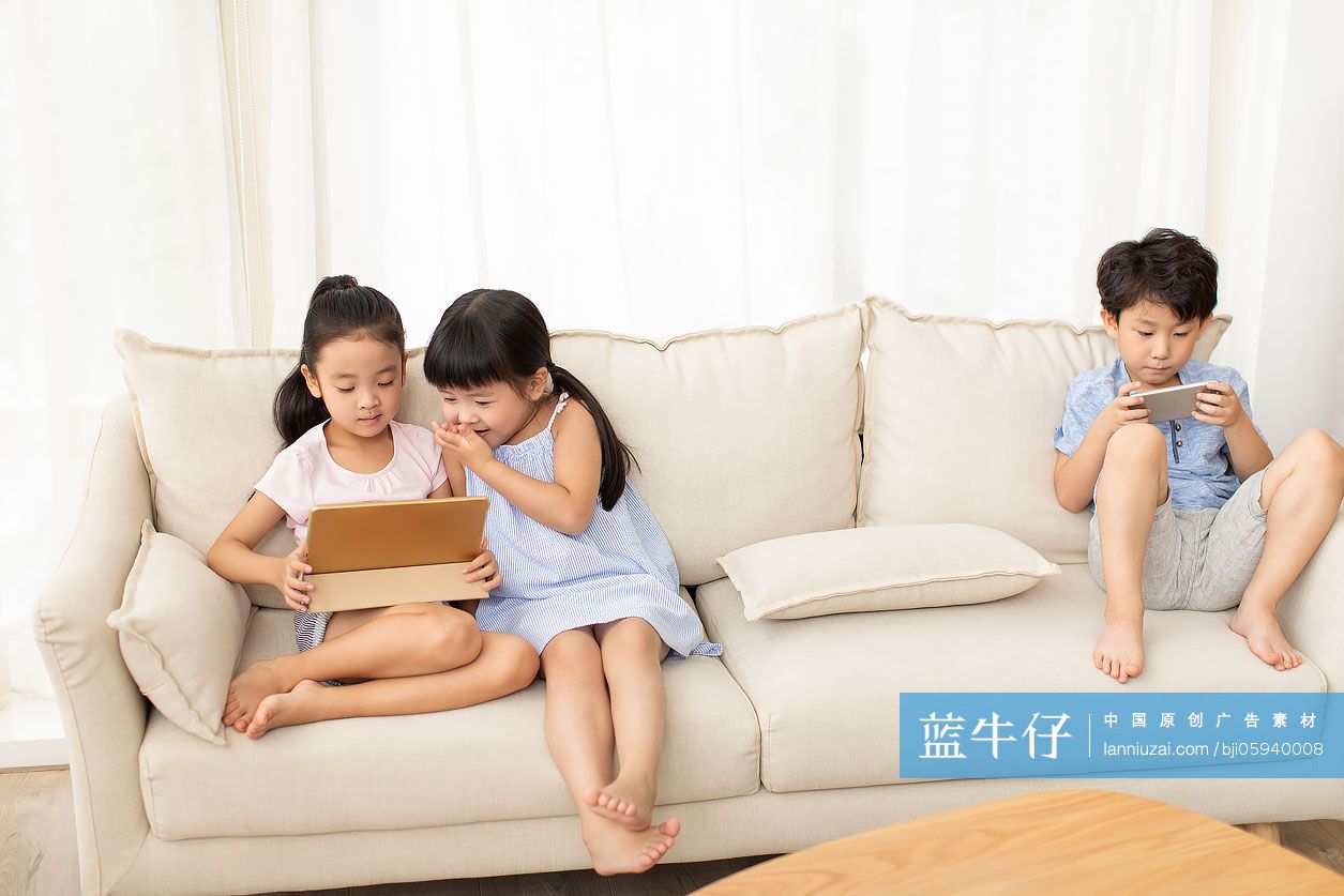 三个小朋友在沙发上玩电子产品