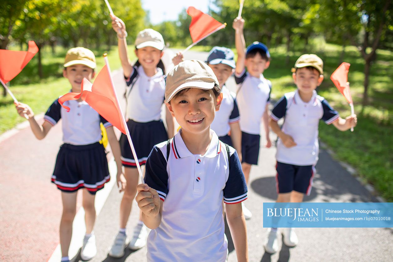 Cheerful Chinese school children relaxing in park