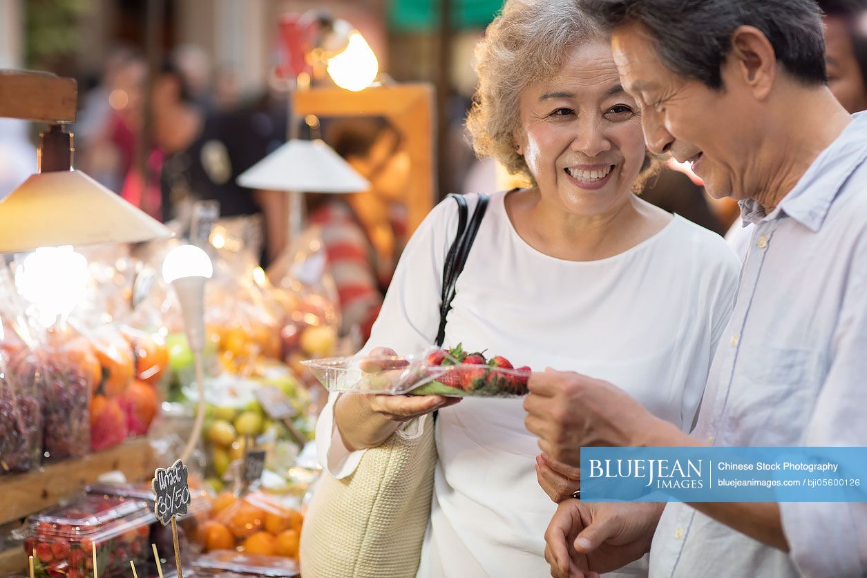 Happy senior Chinese couple relaxing in street market