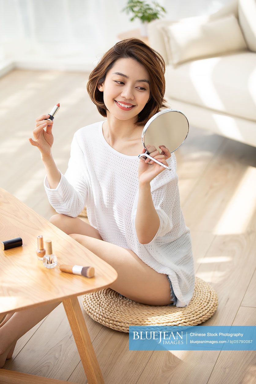 Young Chinese woman applying makeup at home