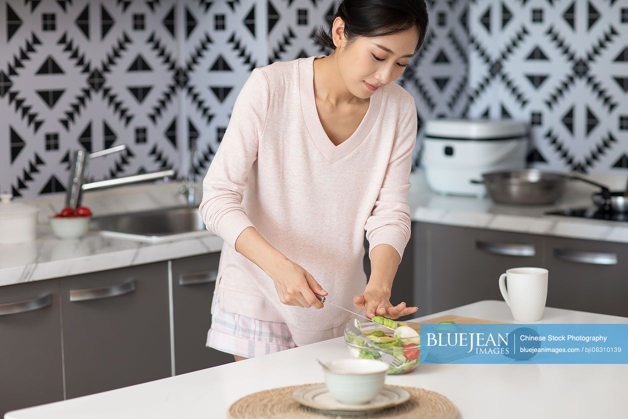Young Chinese woman cooking in kitchen
