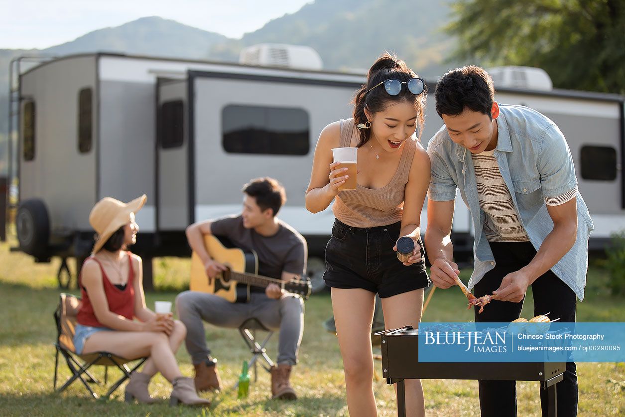 Happy young Chinese friends barbecuing outdoors