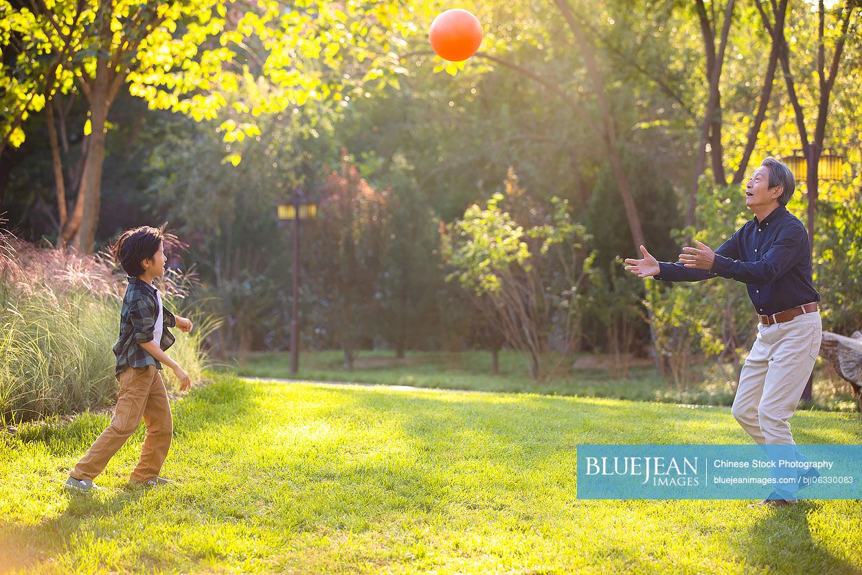 Happy Chinese grandfather and grandson having fun in park