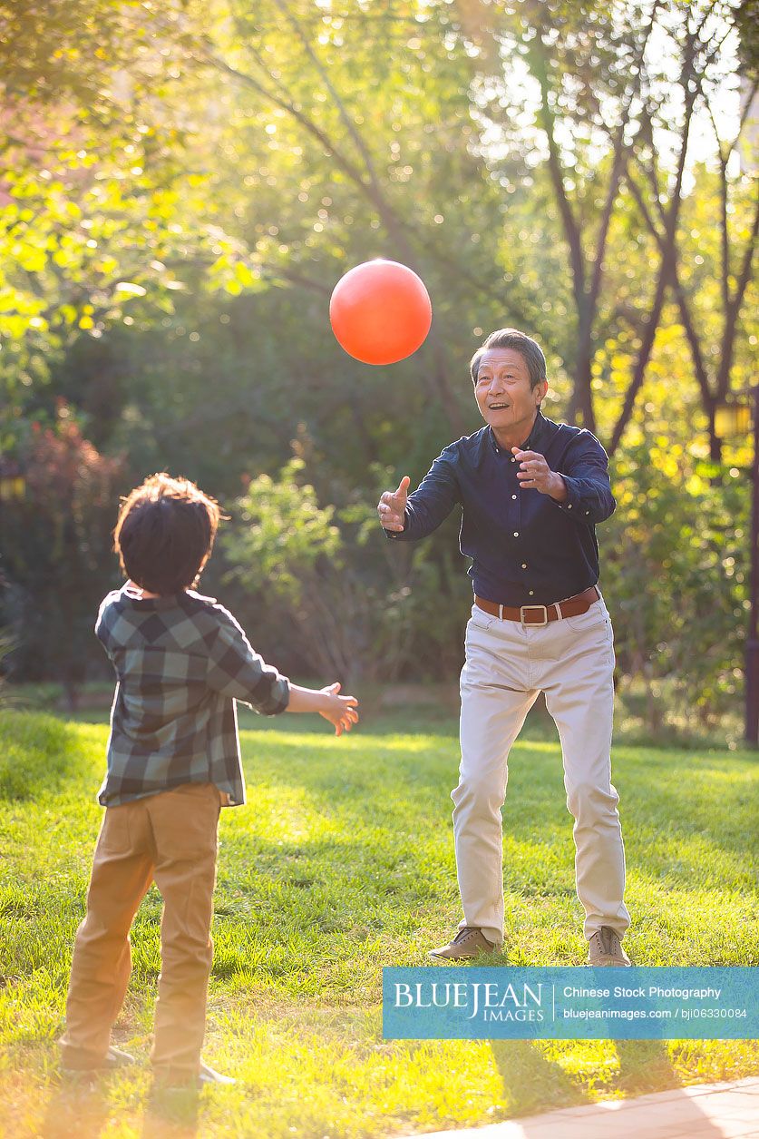 Happy Chinese grandfather and grandson having fun in park