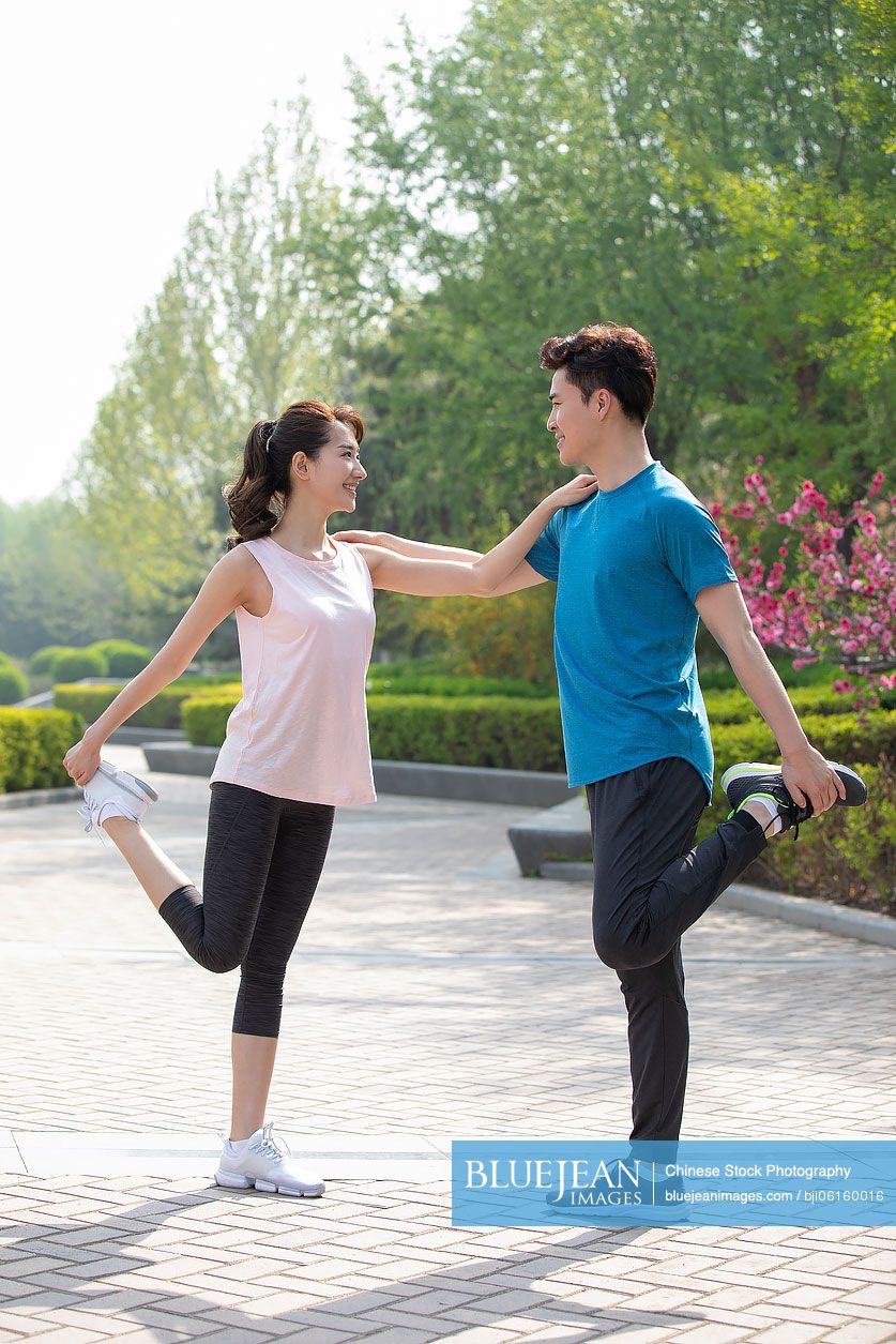 Happy young Chinese couple exercising in park