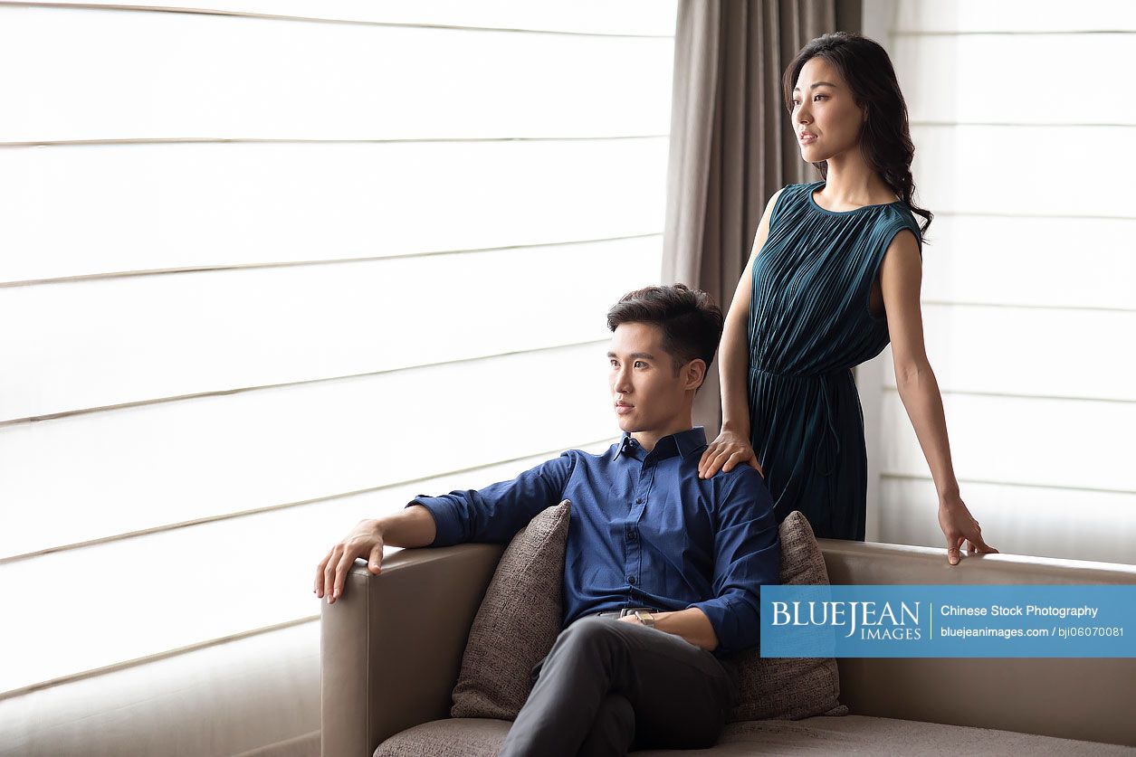 Happy young Chinese couple relaxing in living room