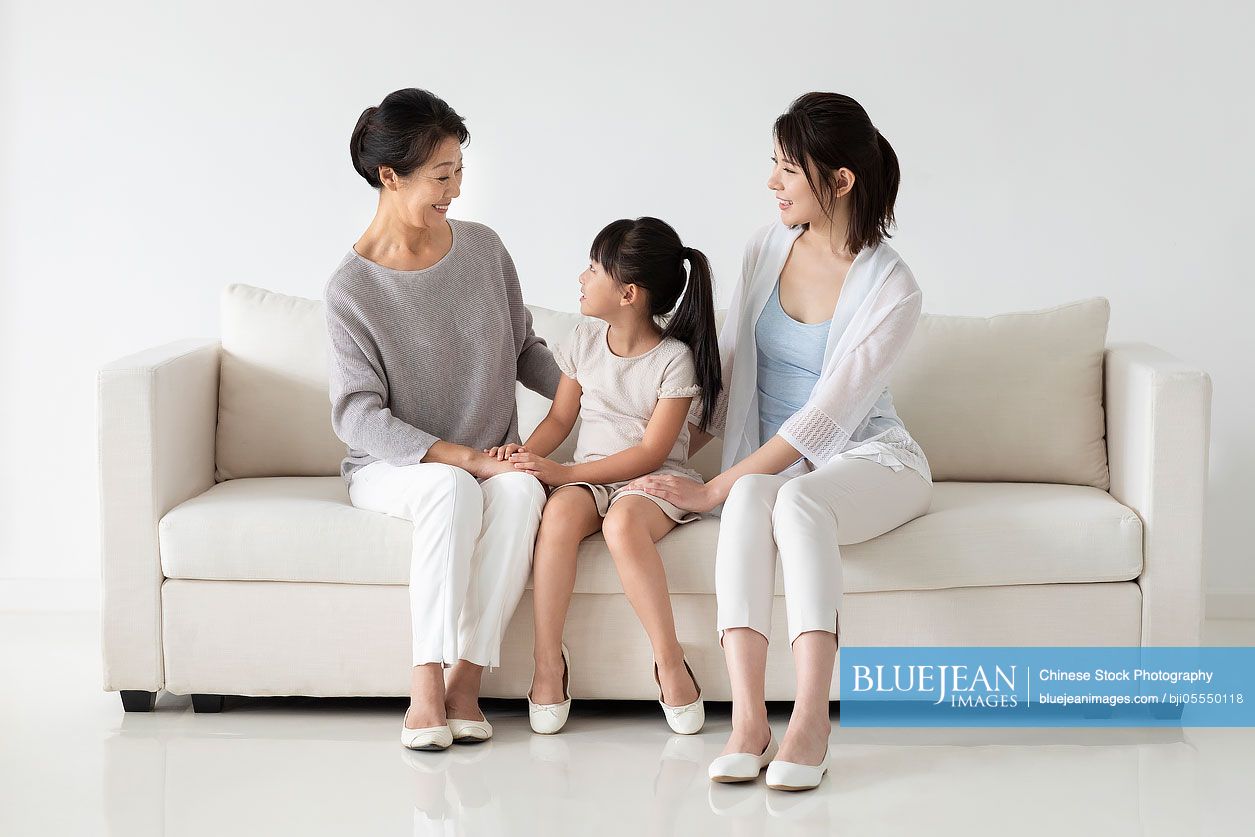 Cheerful Chinese family sitting on sofa