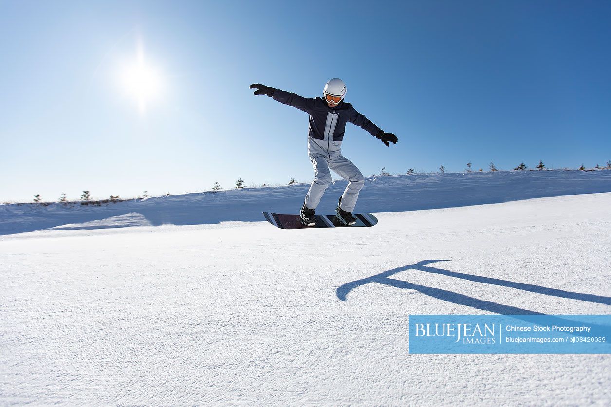 Young Chinese man snowboarding in ski resort