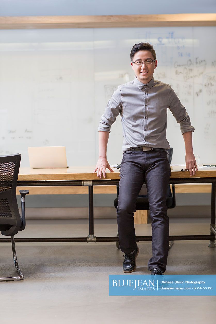 Young Chinese man standing in board room