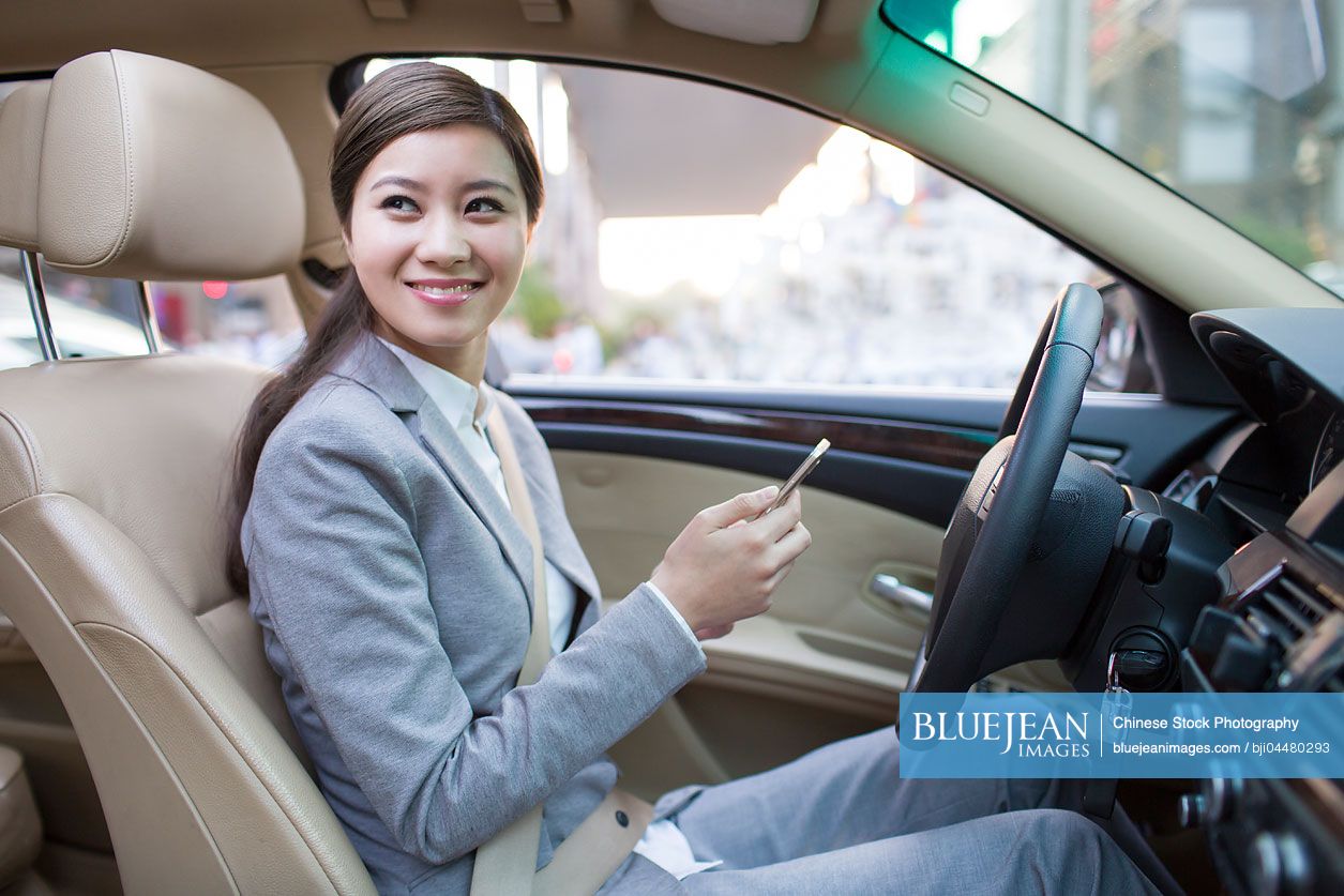Chinese businesswoman holding smart phone in a car