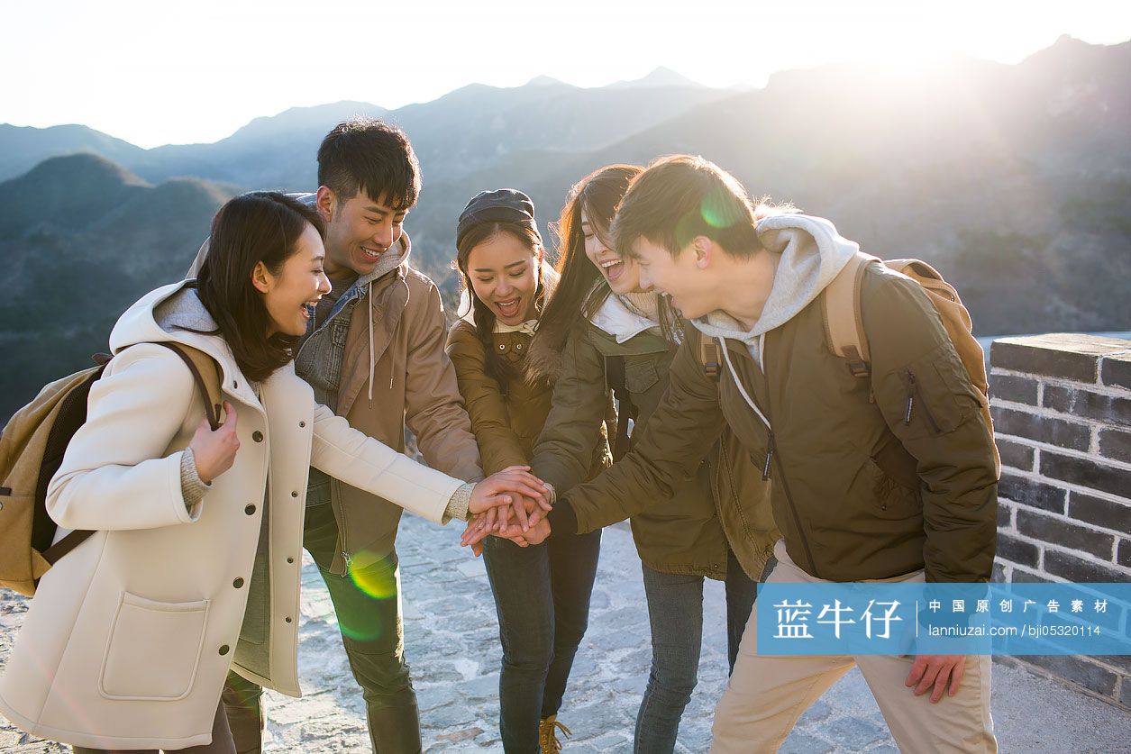 Happy young Chinese friends stacking hands on the Great Wall