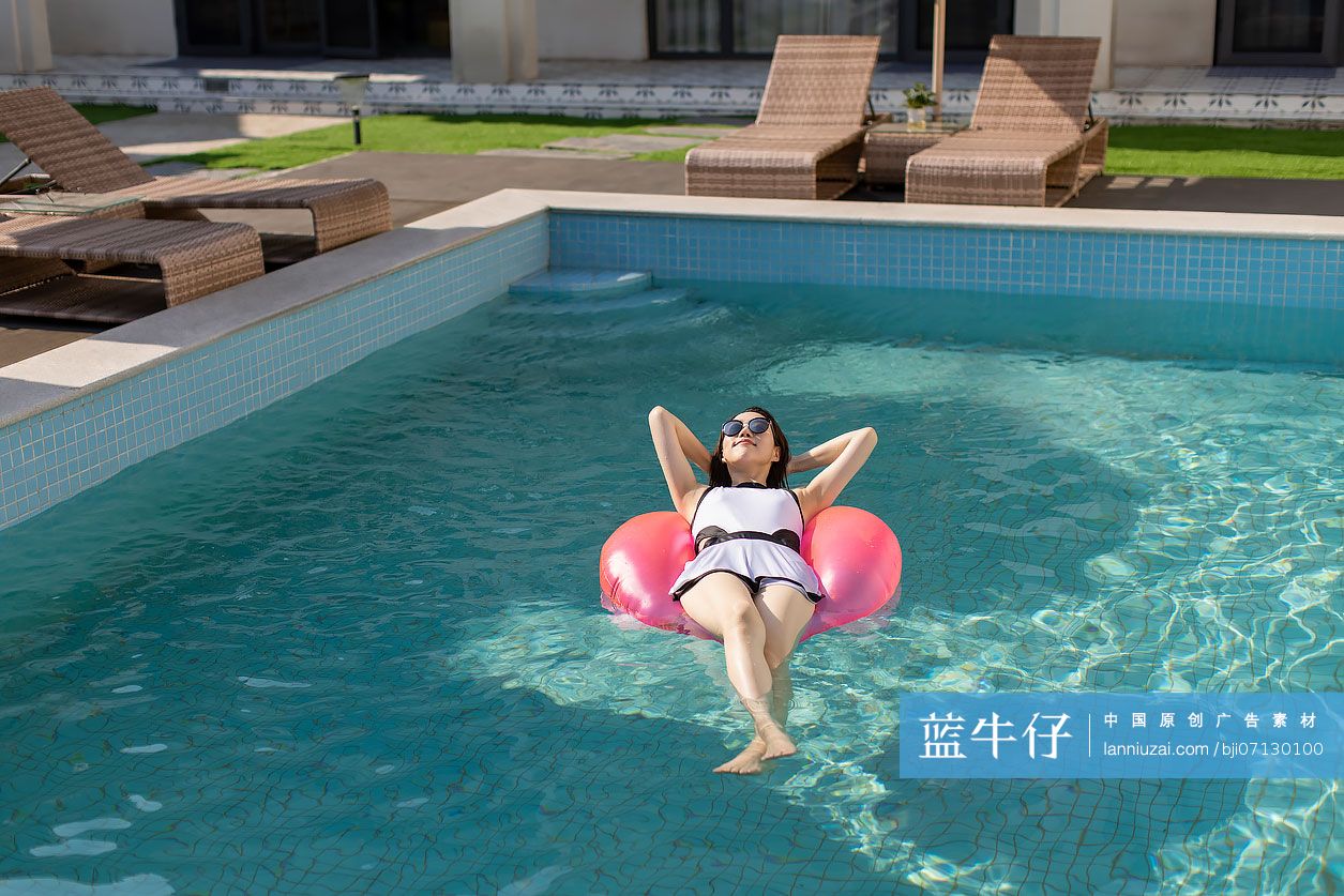 快乐的年轻女子在泳池里晒日光浴