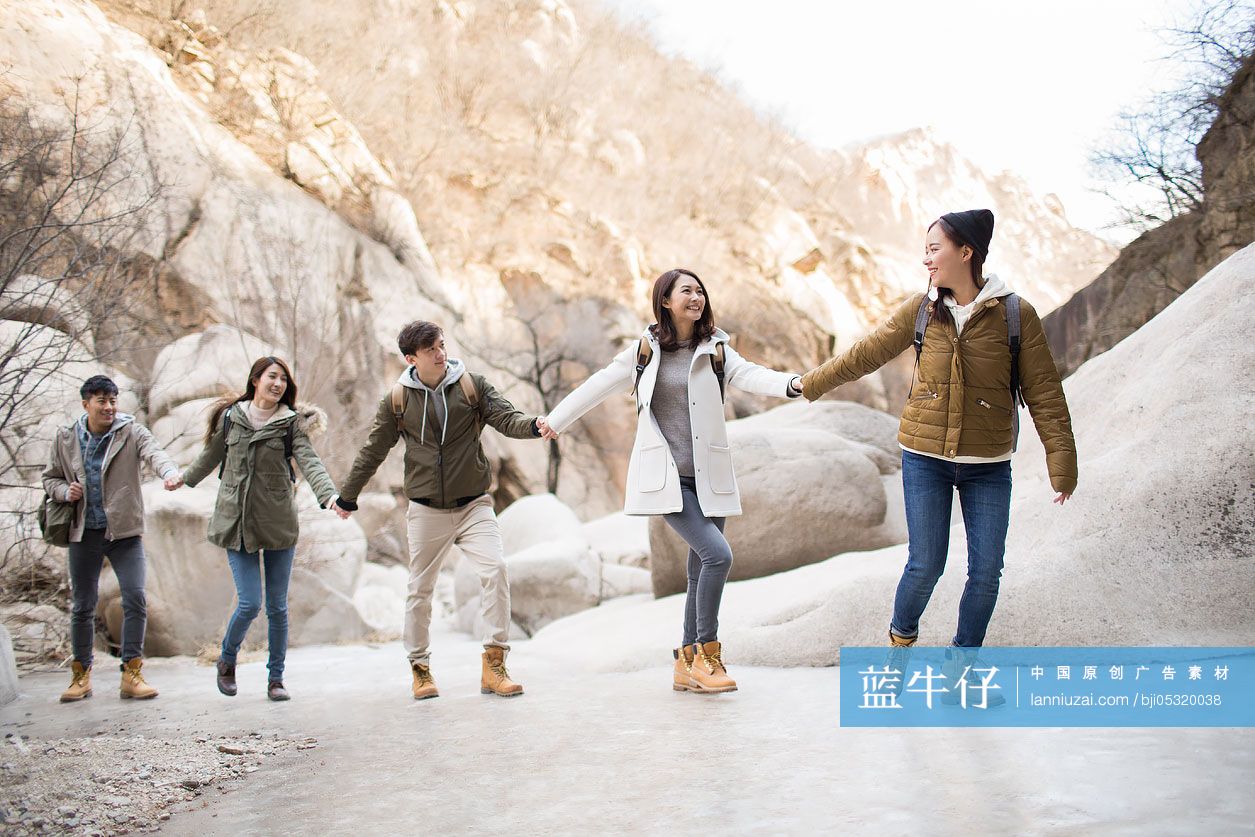 Happy young Chinese friends holding hands enjoying winter outing