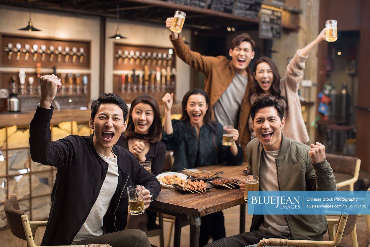 Happy Chinese friends cheering in bar