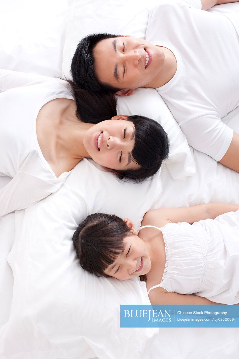 Happy Chinese family lying in bed