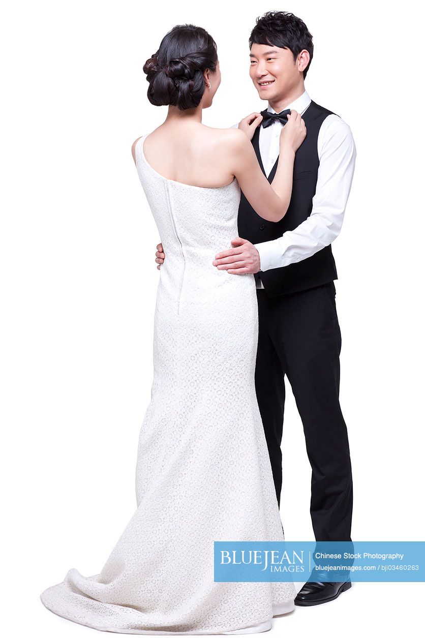 Young Chinese woman adjusting bow tie for man